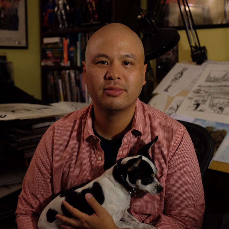 Man holding a small dog in an office setting with artwork on the walls.