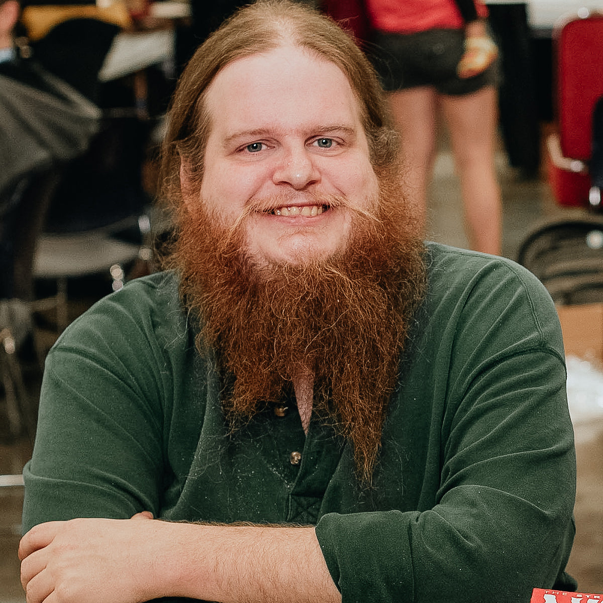 Man with a long beard wearing a green shirt in an indoor setting
