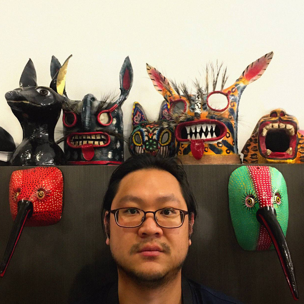 Man standing in front of a shelf displaying various colorful masks.
