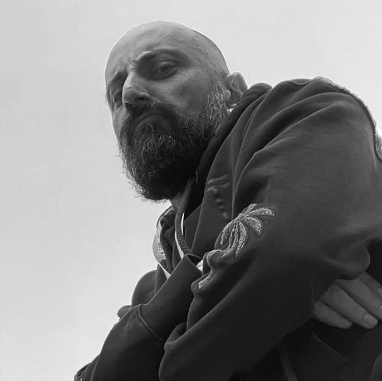 Man wearing a coat with a visible brand logo against a plain background