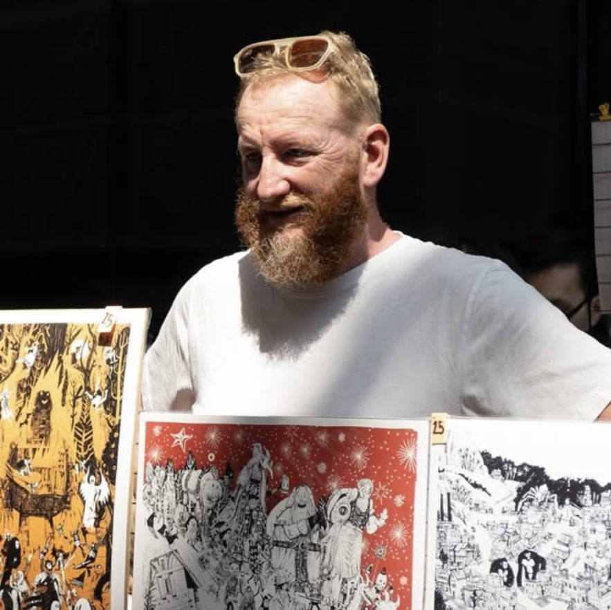 Man with a beard holding prints of artistic illustrations
