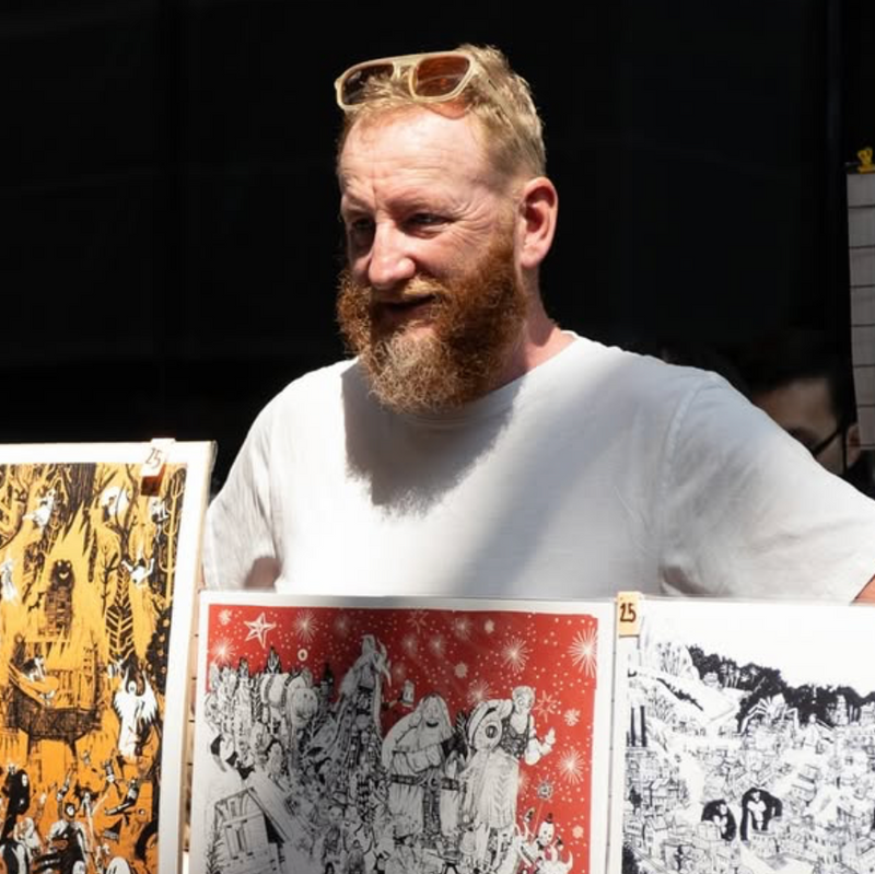 Man with a beard holding prints of artistic illustrations