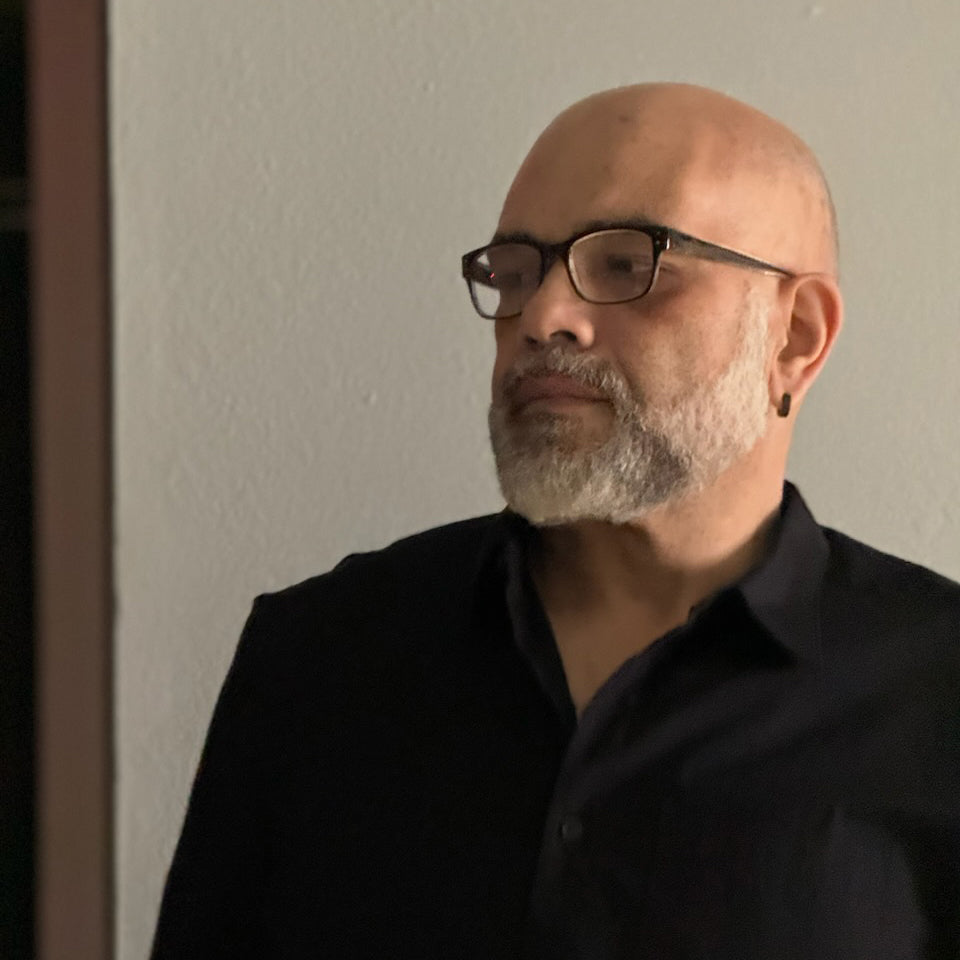 Man wearing glasses and a black shirt against a plain background